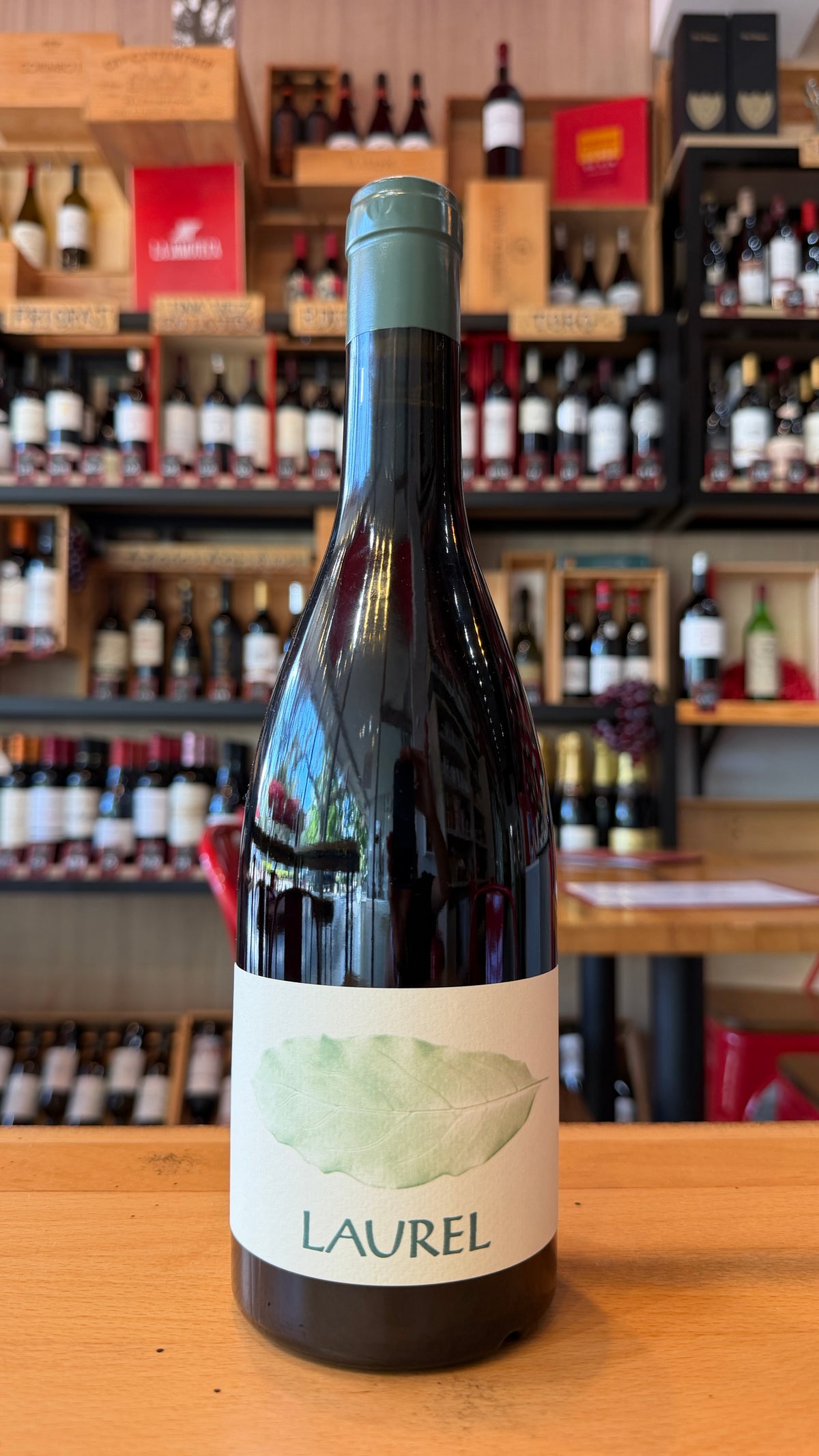 LAUREL, DOC PRIORAT red wine bottle with a green leaf label displayed on a wooden counter in a Spanish wine shop