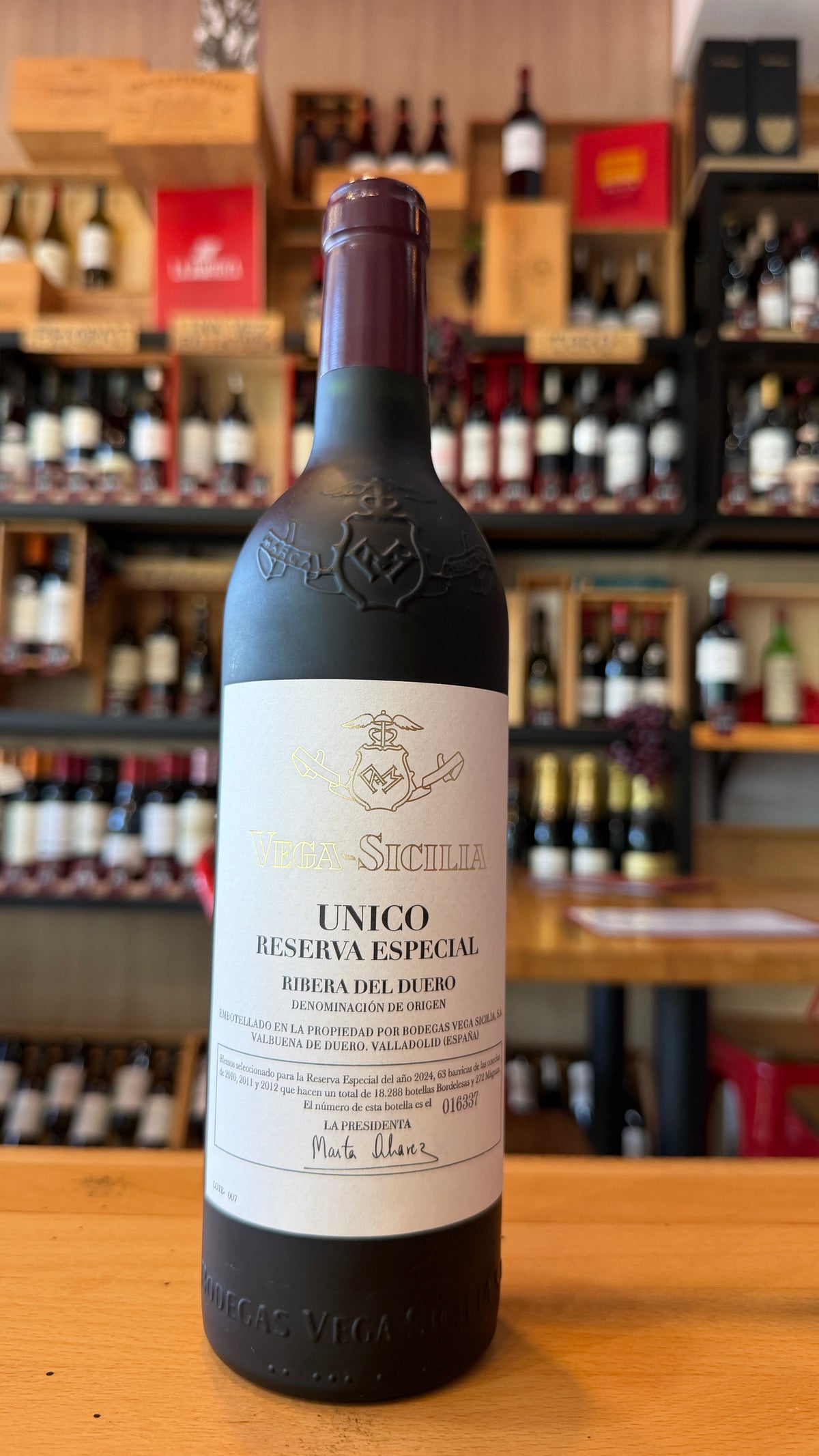 Bottle of UNICO RESERVA ESPECIAL, VEGA SICILIA, RIBERA DEL DUERO wine displayed on a wooden counter in a Spanish specialty shop