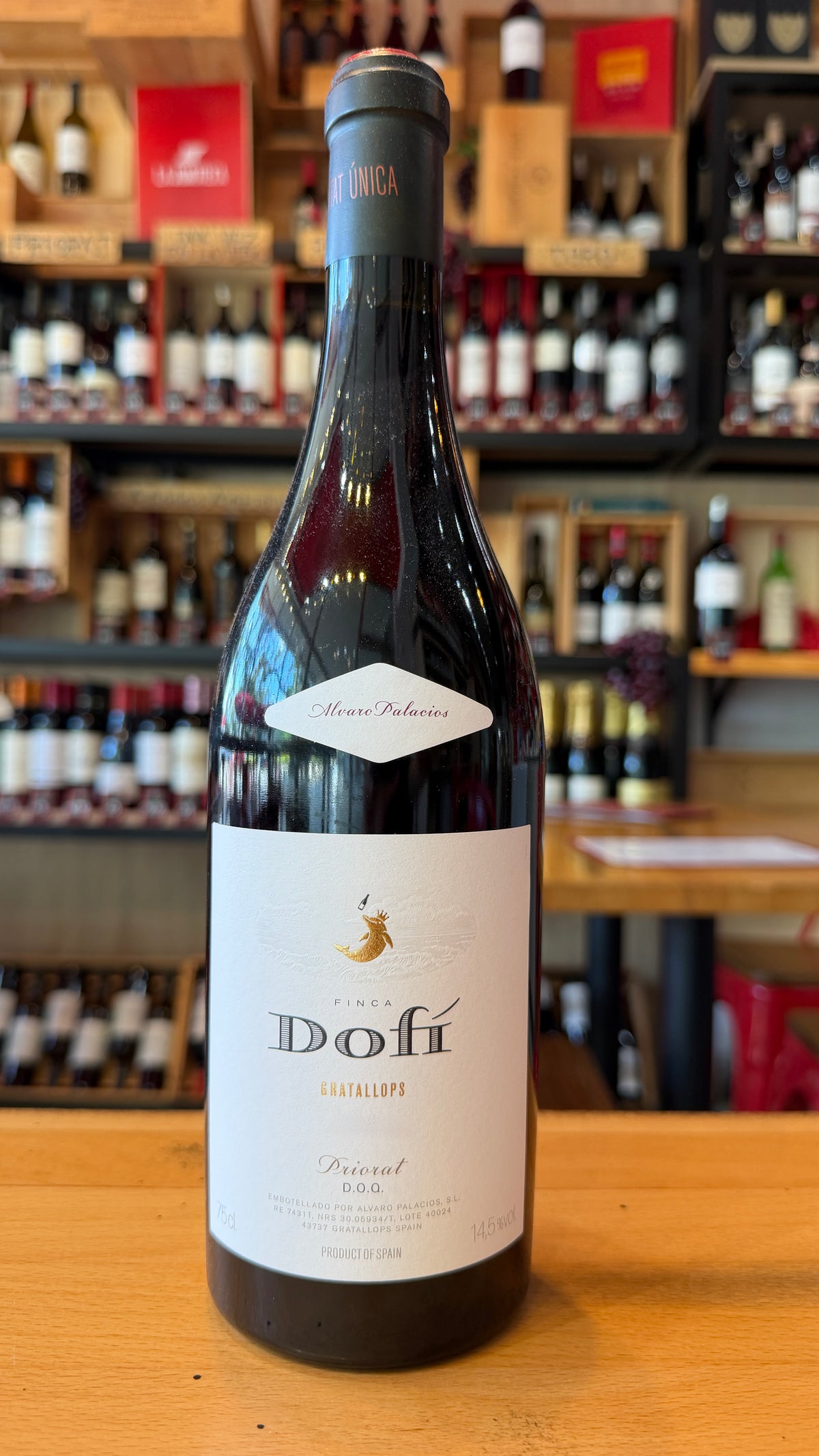 FINCA DOFI, DOC PRIORAT red wine bottle displayed on a wooden counter in a Spanish wine shop